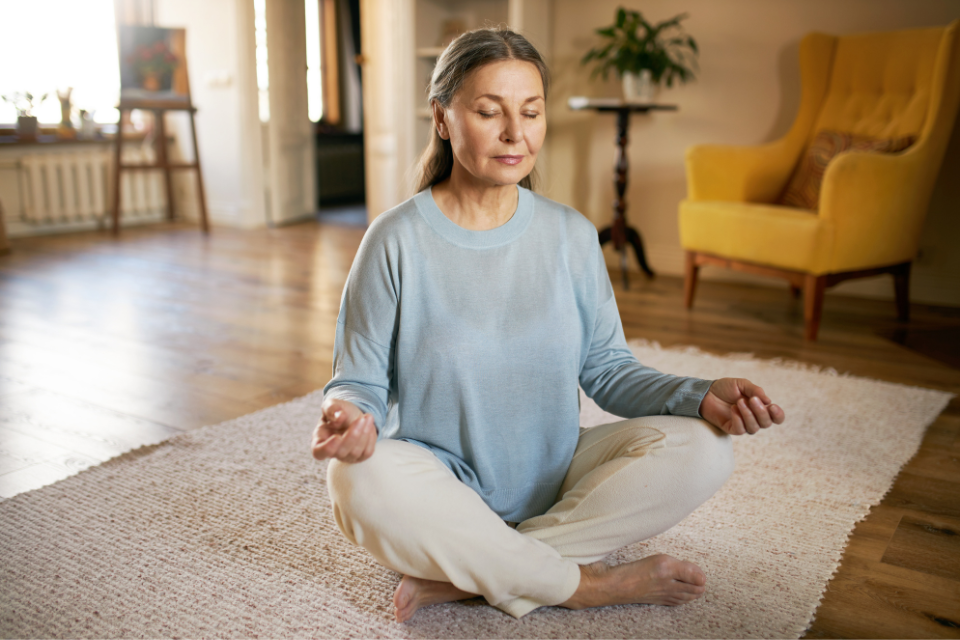 chicago-hearing-services-tinnitus-treatment Woman meditating in a serene living room, promoting relaxation and mindfulness, relevant to tinnitus management and stress reduction techniques.